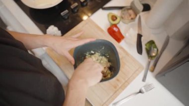 Siyah tişörtlü kadın, Modern Kitchen 'da tahta kesim tahtasında Ton balığını çatalla karıştırıyor.