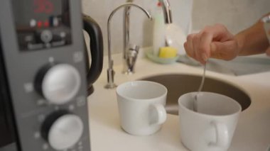 Mutfak lavabosu ve elektrikli su ısıtıcısının yanında, Beyaz Kupanın üzerinde Anında Kahve ile El Tutma Kaşığı