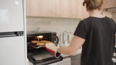 Fırın Eldiveni Giyen Kadın, Modern Mutfak 'ta Taze Tost Ekmeğine Peynir Koyuyor