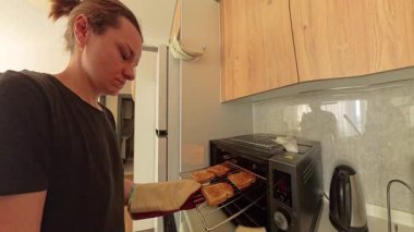 Modern Kitchen 'daki Tost makinesinin içine peynirli sandviç yerleştiren kadın, Geniş Açı Görünüm