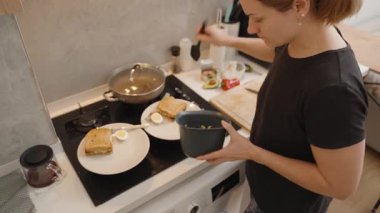 Modern Mutfakta Ton balıklı salata ve kaynamış yumurtalı sandviç servis eden kadın.