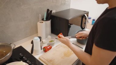 Modern Kitchen Mikrodalga ve fırının yanındaki tahta kesim tahtasında Siyah Tişörtlü Kadın Kırmızı Biber Dilimliyor