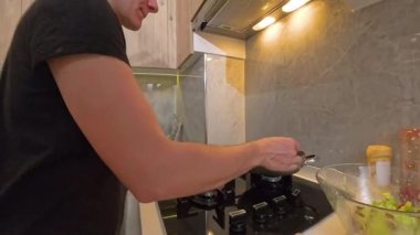 Modern Kitchen 'da çeşitli malzemelerle yemek pişirirken Kara Gömlekli Kadın Gas Sobası' nda Kızartma Tavasına Yumurta Kırıyor. Pişirme Süreci Konsepti