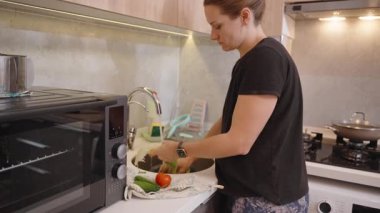 Modern bir Mutfak Yıkama Marulunda Duran ve Lavaboda Sebzeler Giyen, Taze İçindekilerle Yemek Hazırlamaya Odaklanan Kadın