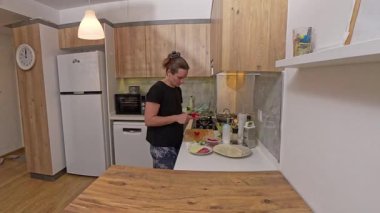 Modern Mutfak 'ta Tahta Kesme Tahtasında Domates Kesen Kadın, Peynir, Sosis ve Tortilla Paketleri Gibi İçindekilerle Bir Tezgahın Yanında Duran Kadın