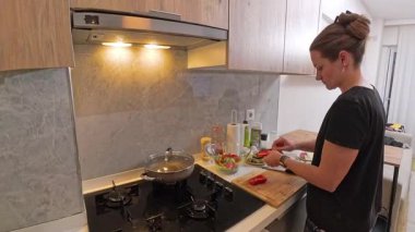 Modern Mutfakta Kırmızı Biber Tutan Kadın, Mutfak Utensilleri ve Fırın ile Tezgahın Yanında Taze Salata İçin İçindekileri Hazırlıyor