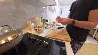 Mutfak tezgahında salata kasesi ve malzemelerle Tahta Kesme Kurulu 'nun yanındaki peyniri tutan kadının yan görüntüsü