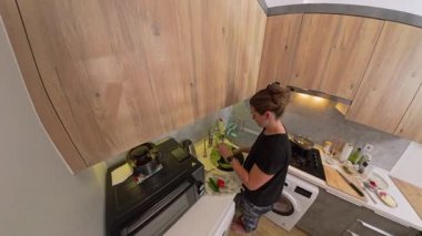 Modern Aletler ve Taze Malzemelerle çevrili, Lavabo Yakınındaki Bir Mutfak Tezgahında Salatalık Kurutan Bir Kadın Görünümü, Bir Smartwatch Giyiyor