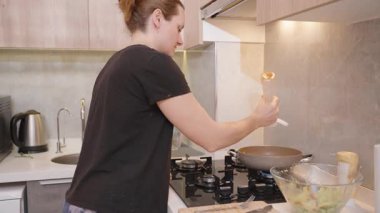 Modern Mutfak 'ta yemek hazırlarken, Siyah Gömlekli Kadın Kızartma Tavasına Sos Sıkar. Pişirme Süreci Konsepti