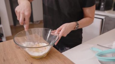 Unu, şekeri ve yumurta sarısını ahşap mutfak tezgahında karıştırmak için çırpıcıyı kullanan kadının yakın çekimi.