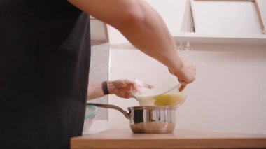 Cam kaseden, ahşap mutfak tezgahındaki Paslanmaz Çelik Tencereye Koyu Dökümlü Kadın 'ın Yakın Çekimi Tek Elde Fıçıyı Tutuyor