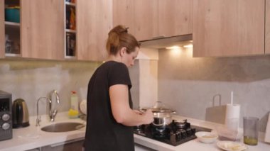 Modern Mutfak 'ta bir tencereyi ocakta karıştıran kadın, Odaklanmış İfade, İçindekiler ve Tezgâh Tarifi Kitabı