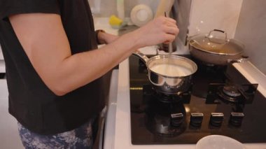 Paslanmaz çelikten bir tencerede çırpılmış sosu çırpılmış çırpılmış çırpılmış çırpılmış bir kadının yakın çekimi.