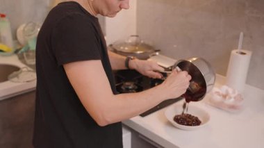 Koyu Meyve Karışımı 'nı Mutfak tezgahında Beyaz Kase' ye, Yumurta Kabuğu ve Yemek Aletleri 'ne döken Kadın