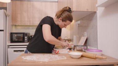 Ahşap mutfak tezgahına un serpiştiren kadın, Arkaplanda Rolling Pin ve İçindekiler