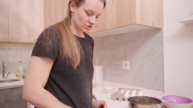 Un kaplı mutfak tezgahında tahta raptiyeli küçük bir hamur parçası yuvarlayan kadın.