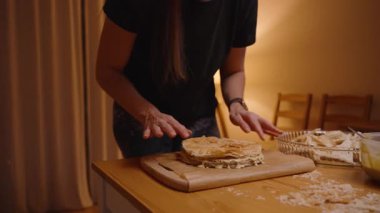 Ahşap masa üzerinde ev yapımı bir tatlıyı birleştirirken Katmanlı Pastaya Krema Döken Kadın