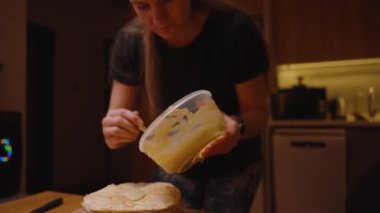 Sıcak Mutfaktaki Ahşap Masada Katmanlı Pastaya Muhallebi Uygulayan Kadın