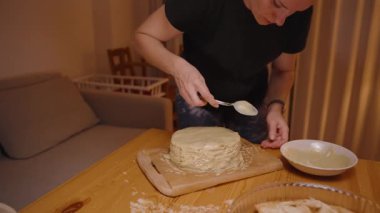 Kekin üzerindeki kremalı kaplamayı bitiren kadın tahta kesme tahtasında kaşık ile