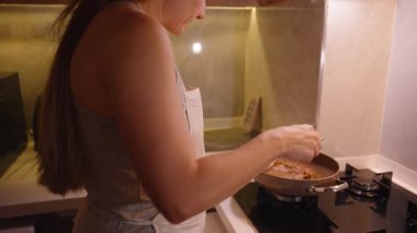 Ahşap kesme tahtasının üzerinde elinde kadın maşasıyla pişirilmiş biftek dinleniyor.