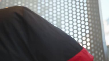 Kırmızı ve Siyah Ceketli Adam Lokanta Masasında Odaklanmış İfade 'de otururken Pipetle Buzlu Kahve İçiyor