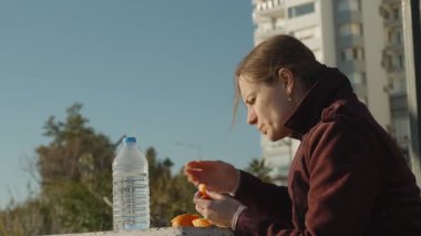 Bir Masada Oturan Kadın Bir Şişe Suyu ve Arka planda Manzarası Olan Mandalina Bölümü