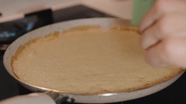 Silikonlu Spatula kullanan bir kadın gaz ocağında yapışmaz tavada ince bir krep çeviriyor.