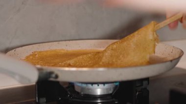 İnce, kahverengi bir krepi sobadaki yapışmaz tavadan çıkarmak için ahşap bir Spatula kullanmak