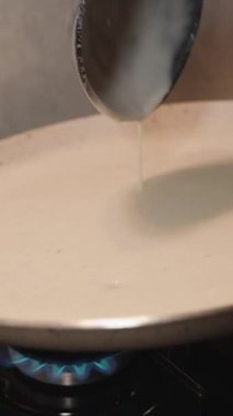 Dikey video. Yüzeyde küçük hava kabarcıkları oluşturan büyük yapışmaz tavada krep hamuru pişirme
