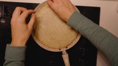 İnce bir krepi yapışmaz tavayla gaz sobasında çeviren bir kadının genel görünümü