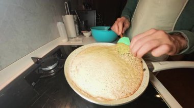 Benzin ocağında Silikonlu Spatula ile Altın Kahverengi Krep Çeviren Kadın