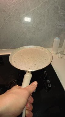 Dikey video. Bir kadının krep hamurunu bir kepçeden eğik bir teneke kutuya döken ilk insan görüntüsü.