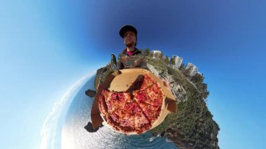 Küçük Gezegen Efektli Bir Pizza Kutusu Tutan Adam, Arka planda Eşsiz 360 derecelik Okyanus, Kayalıklar ve Binalar Görünümü Oluşturuyor