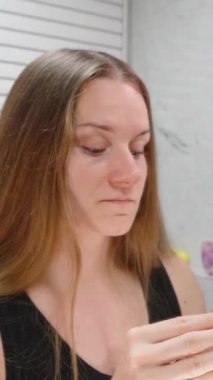 Dikey video. Aynaya Bakan Kadın Uyku Geliştirme için Göz Seviyesi Konseptinden Yatmadan Önce İki Elinle Siyah Ağız Bandını Uyutuyor