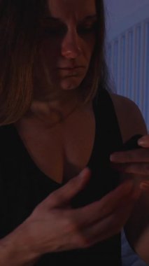 Dikey video. Karanlık Yatak Odası 'ndaki Kadın Rehine Bantına Basıyor Nefeslenebilir Ağız Bandı Gece Mavisi İçin Mavi Işıkla Uyumadan Önce Dudaklara Bantlıyor