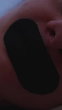 Dikey video. Derin Burun Nefes Alma Konsepti İçin Düşük Işık Altında Genişleyen Burun delikleriyle Nefes Akan Ağız Bandı Giyen Uyuyan Kadının Yakın Çekimi