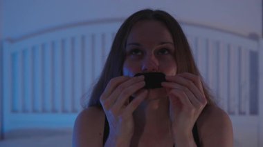 Gece Uykusuna Hazırlık Konsepti için Yatakta Oturan Kadın Ağzına Bant Bantla İki Elinle Loş Mavi Işıkta