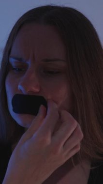 Dikey video. Loş Işık Altındaki Kadın Ağız Bandını Acı İfadeyle Kaldırıyor Yatakta Otururken Uyku Yardımı İnceleme Konseptinden Rahatsız Olduğunu Gösteriyor