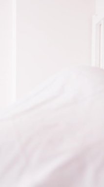 Dikey video. Gündüz Uyku Sağlığı Konsepti için Beyaz Battaniyeyle Kapalı Parlak Yatak Odasında Ağzı Bantlı Uyuyan Kadın