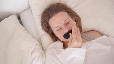 Parlak Uyku Yardımı Değerlendirme Odasında Yapışkan Rahatsızlıktan Tereddüt Ederken Bir Kadın Uyanıp Ağız Bandını Çıkartıyor