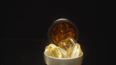 Dolly Kamera, arka planda açık bir şişe ile Omega 3 kapsülünden bir Omega 3 kapsülünü alıp karanlık bir ayar içinde bir Makro-yakın çekim yakalıyor.