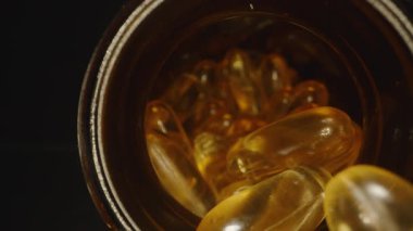 Dolly Kamera, Parmaklar Şişeden Bir Omega 3 Kapsülü Çıkarırken Hareket Ediyor, Saydam Jel Kapsülünün Arka planda Görünür Daha Fazla Kapsüllü Makro Yakın Çekimini Gösteriyor