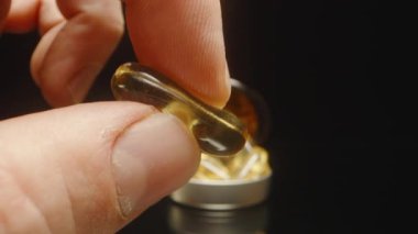 Parmaklar Bir Omega 3 Kapsülü Sıkarak Yumuşaklığını ve Esnekliğini Bir Makro Yakın plan Kapsülü ile Sıkarak Arkaplanda Isınma Altında ve Karanlık Arkaplan