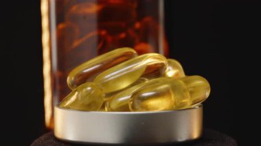 Kahverengi bir Cam Şişenin Önünde İçi Omega 3 Kapsülle Dolu Bir Şişe Kapağının 360 derecelik Dönüşü Ilık Işık Yansımalı Karanlık Bir Arkaplana Karşı