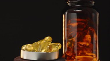 Bir şişe kapağının 360 derecelik Dönüşü Şeffaf Kahverengi Cam Şişe Önünde Omega 3 Kapsülle Doldurulmuş Karanlık Arkaplan Karşısında