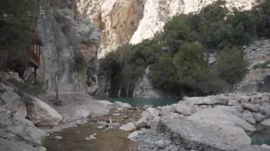 Berrak Turkuaz Nehri, Bereketli Yeşillik ve Dik Güneş Işığı Altındaki Uçurumlar ile Rocky Kanyonu 'ndan akıyor Küçük Akıntı, Nehirle Önplanda Birleşiyor, Geniş Açı Görüş