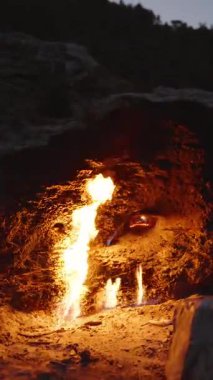 Dikey video. Türkiye 'deki Chimaera' da bulunan Kayalık Yüzeyden Sonsuz Alevler, Çevre Taşı 'nı sıcak bir parıltıyla aydınlatarak, Gizemli Doğal Manzara' da Karanlık 'ta Yakalandı