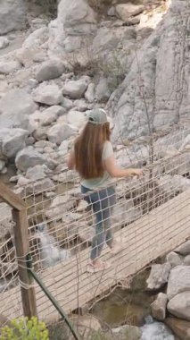 Dikey video. Dar İp Üzerinde Yürüyen Kadın Kayalık Kanyon 'da Bir Yan Açı, Macera ve Keşif Konsepti' nden Çekilen Tedbirli Duruş ile Askı Köprüsü Üzerinde Yürüyor