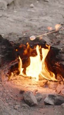 Dikey video. Türkiye 'deki Chimaera' da Doğal Alevler Üzerine Şekerlemeleri Kızartan Kişi, Açık Hava Kayalıklarında Kayalık Yemek Pişirmek İçin Yeraltı Gaz Yangınlarını Kullanıyor