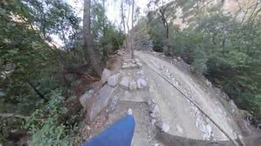 Dar Kayalıklarda Yürüyen Bir Kadının İlk Görüş Alanı Kanyon 'da Dik bir yamaç boyunca Rocky Patikası, Denge için Güvenlik İpine Tutulma, Ağaçlar ve Kayalarla çevrili, 360 derecelik Kamera